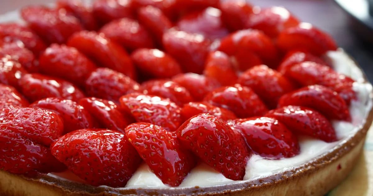 Crostata di fragole rosse lucide su crema bianca e base dorata vista ravvicinata
