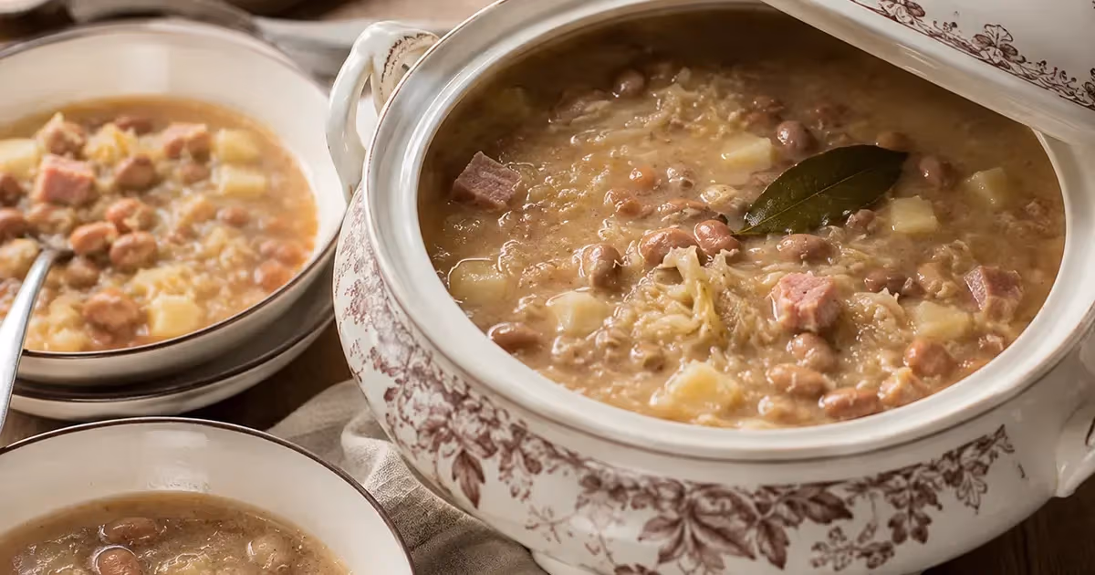 Jota triestina densa con fagioli borlotti crauti patate e carne affumicata in zuppiera bianca floreale