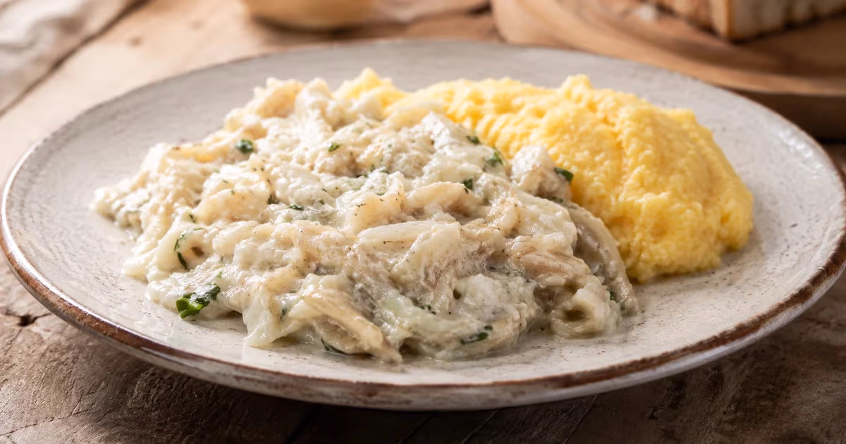 Baccalà mantecato cremoso con prezzemolo servito accanto a polenta gialla su piatto rustico